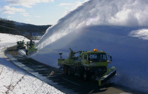 除雪トラック（マックレー装置）にて切り崩した雪をロータリ除雪車にて投雪している状況
