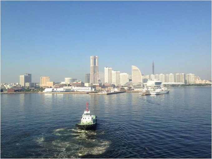 タグボートに曳航されて、横浜港大桟橋国際客船ターミナルへ（後方はランドマークタワー）