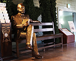 木製ベンチに座るクラーク博士の銅像の写真