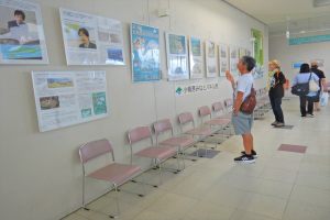 港に関するパネルを眺める観光客