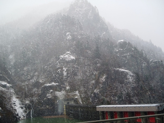 ダム近辺の山に雪が降った写真